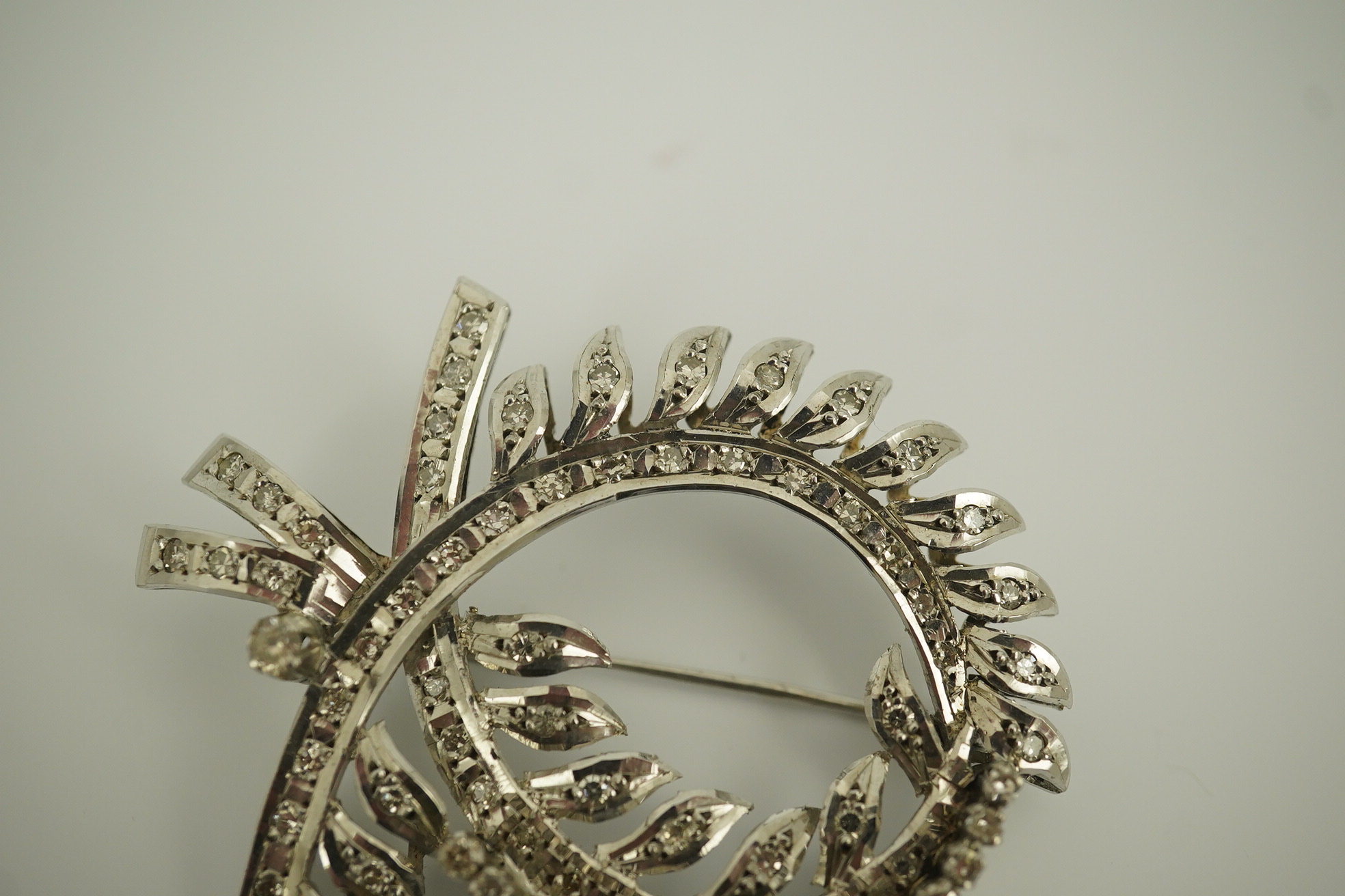 A recent white gold and diamond cluster set scrolling wreath brooch